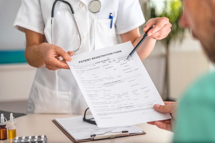 A Doctor Is Pointing At A Patient Registration Form