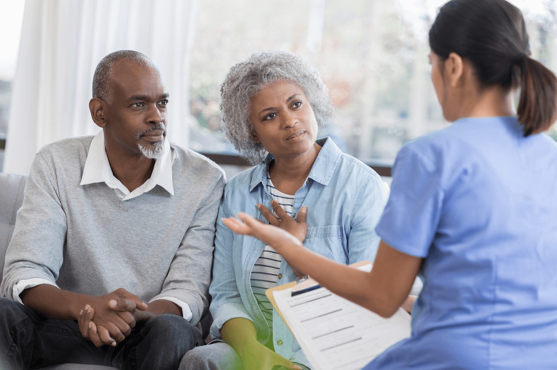 A Man And Woman Sit On A Couch Talking To A Nurse