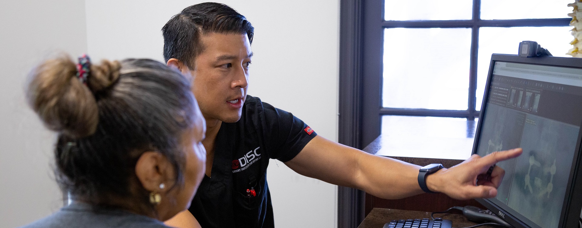 Dr. Wang Wearing A Shirt That Says DISC Is Pointing At A Computer Screen